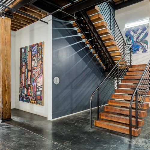 The Mitchell The stairway and halls at the Mitchell Lofts in Deep Ellum, Dallas, featuring brick walls and a painted mural.