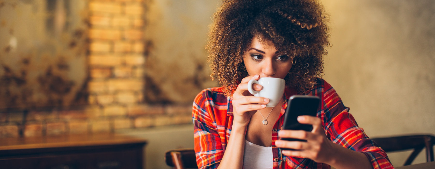 Woman drinking coffee while on phone.